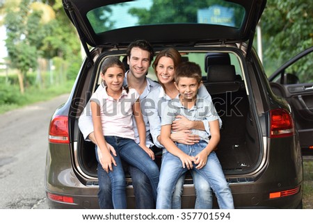 Family sitting in car trunk, ready for vacation