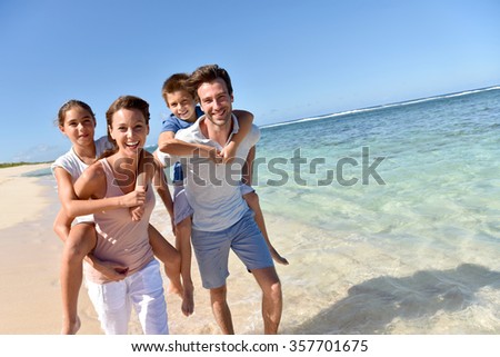 Parents giving piggyback ride to kids on a sandy beach