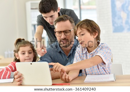 Teacher with students in class using digital tablet