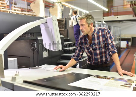Man working on printing machine in print factory