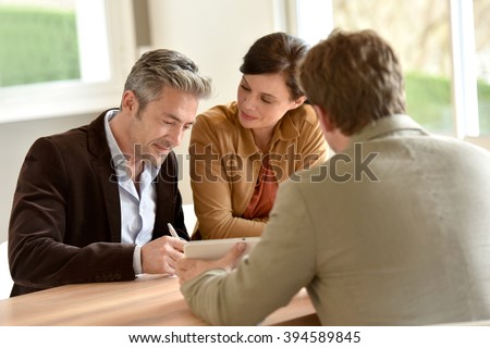 Mature couple signing documents in real-estate agency
