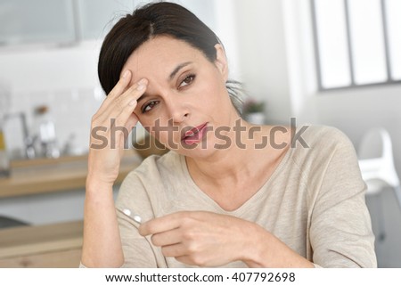 Woman having headache, taking pills