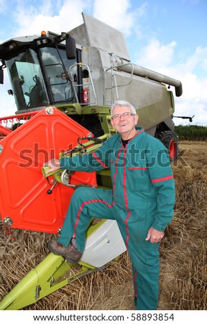 Farmer in wheat field in front of harvesting machine