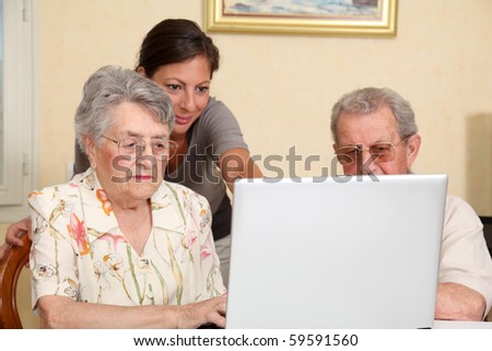 Couple of elderly persons with young woman using internet