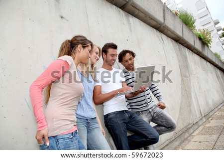 Group of friends standing against wall with laptop computer