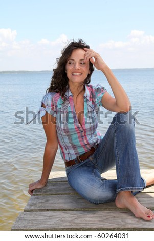 Woman sitting on a pontoon by a lake in summer