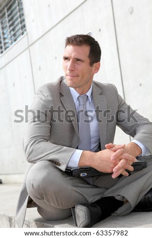 Salesman sitting cross-legged in front of building