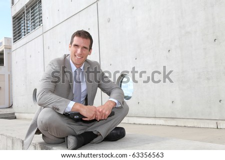 Salesman sitting cross-legged in front of building
