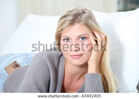 Smiling beautiful blond woman laying on sofa