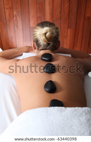 Blond woman laying on massage bed with hot stones
