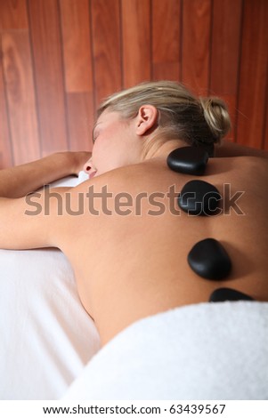 Blond woman laying on massage bed with hot stones