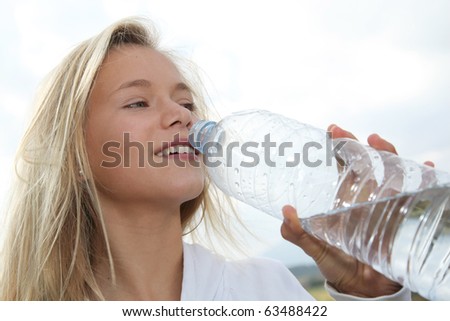 Closeup of beautiful blond girl drinking water from bottle
