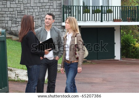 real estate agent clipart. stock photo : Couple and real-estate agent in front of house for sale