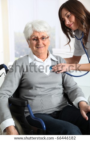 Elderly woman in wheelchair with nurse at home