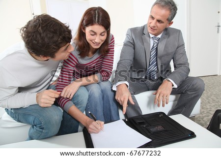 Young couple signing renting contract with real estate agent