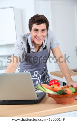 Man in kitchen looking at recipe on internet