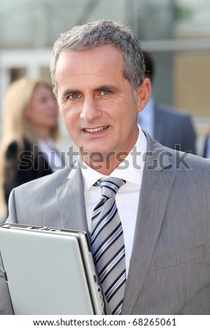 Businessman standing outside with laptop computer