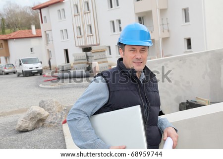 Site supervisor with security helmet standing on construction site