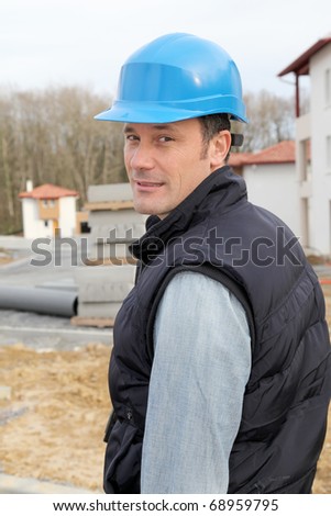 Site supervisor with security helmet standing on construction site
