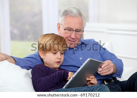 Grandpa with little boy using electronic tablet