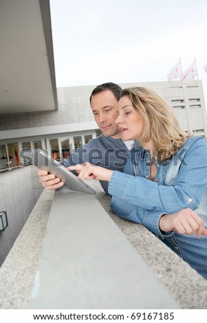 Couple using electronic tab in the street