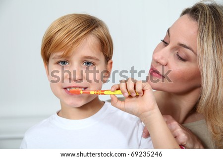 Mother teaching little boy to brush his teeth