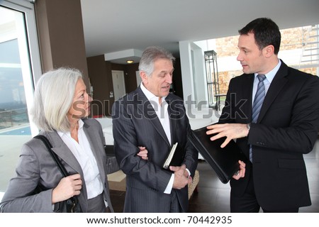 Senior couple visiting modern house with real-estate agent