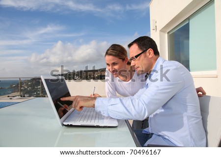 Couple using laptop computer outside the house