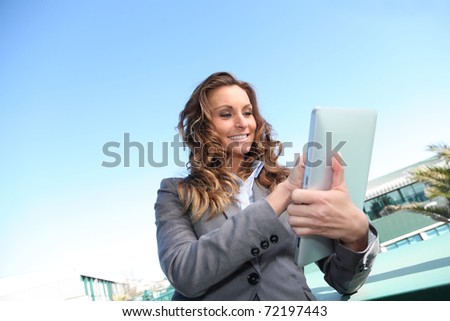Smiling businesswoman using electronic tablet outside