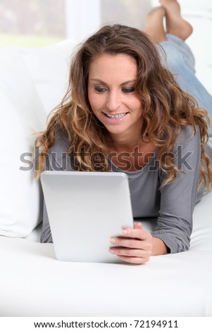 Beautiful woman laying on sofa with electronic tablet