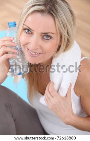 Beautiful blond woman drinking water after exercising