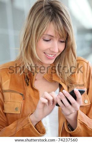 Woman in town sending short message with mobile phone