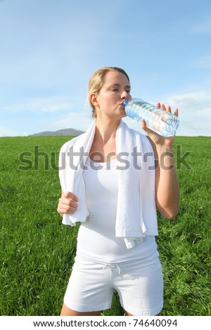 Woman drinking water from water during fitness activity