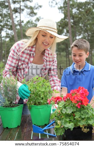 Mother and child planting flowers in house garden