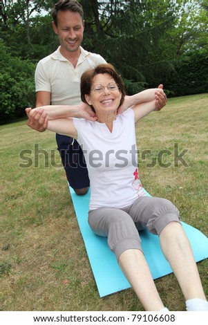 Sports coach training senior woman with stretching exercises