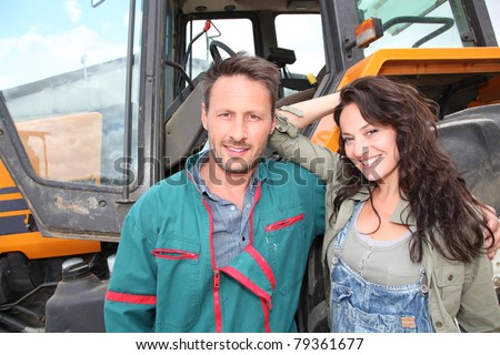 Farming couple standing by tractor