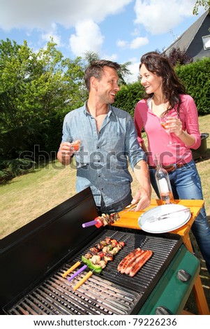 Happy couple cooking meat on barbecue grill