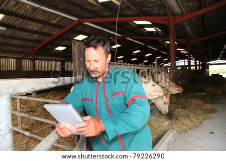 Farmer in barn using electronic tablet