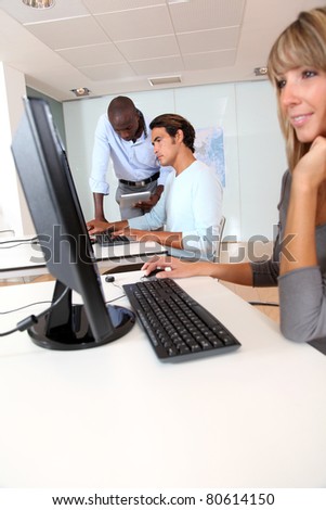 Blond woman sitting in front of desktop in office