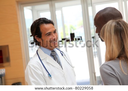 Doctor talking to couple in hospital hall