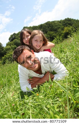 Man lying down in park with girls on his back