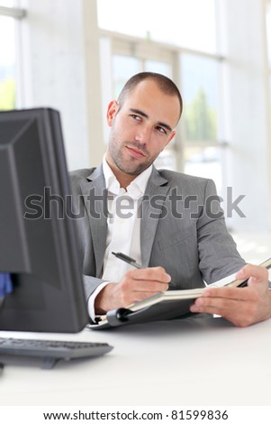 Businessman in office writing on agenda