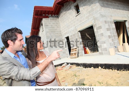 Happy couple standing in front of house under construction