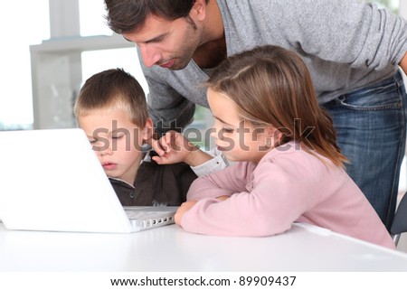 Man teaching kids how to use laptop computer
