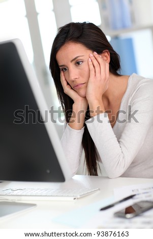 Woman in front of desktop computer having a headache