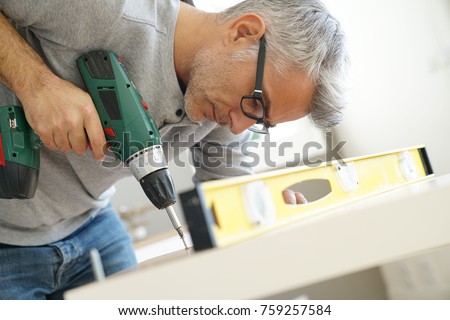 Man assembling DIY furniture using electric drill