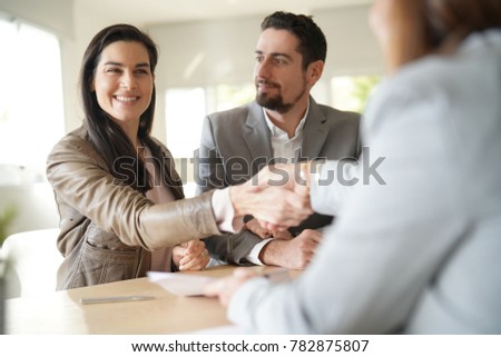 Couple in bank office signing loan agreement