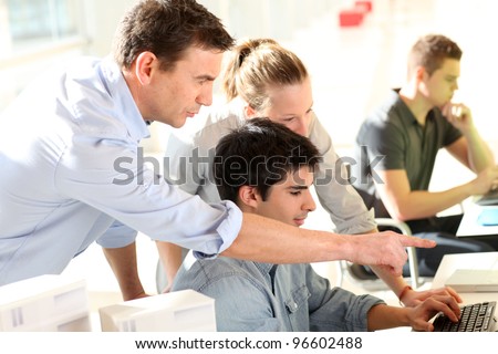 Students with teacher in front of desktop computer