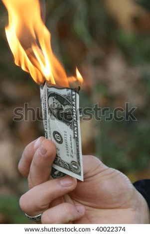 Man holding a dollar bill burning