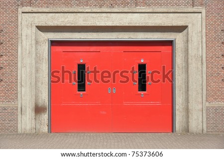 Closed solid red doors in a red brick wall